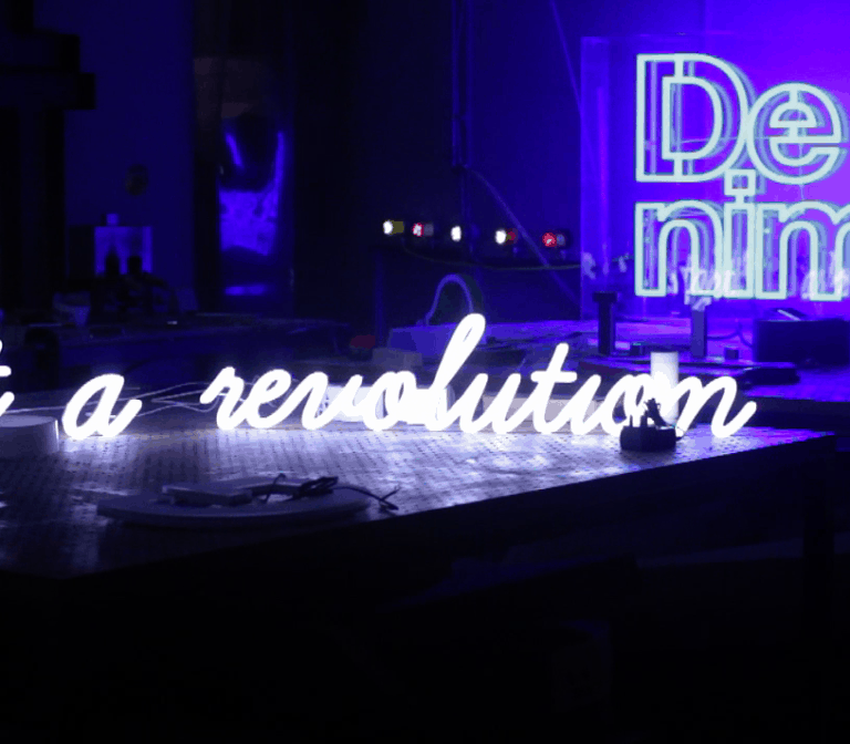 Script lettering on workbench says 'start a revolution', illuminated white