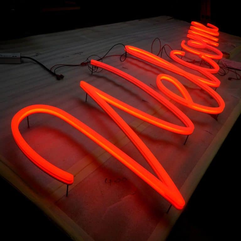 Cursive 'Welcome' neon style sign for hotel, illuminated with orange LEDs