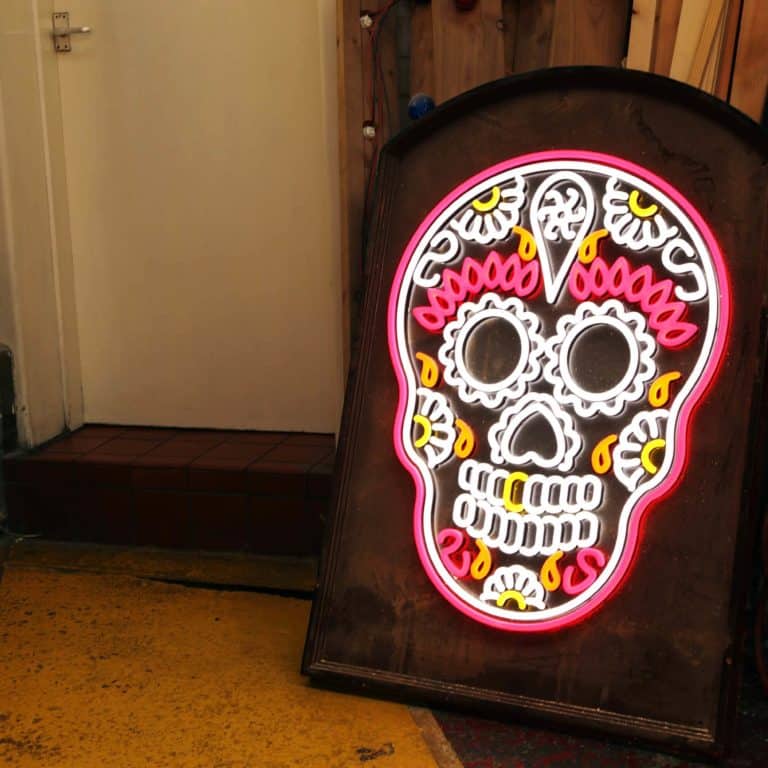 Pink and yellow faux neon sugar skull gravestone sign. Dia de lost Muertos skull neon signs in pink white and yellow.