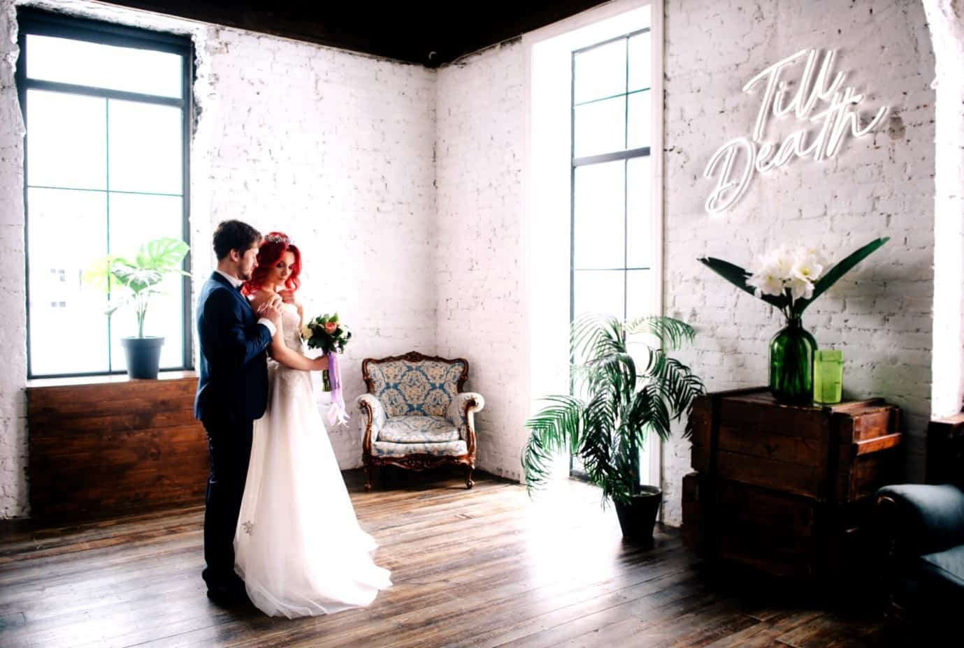 A Married couple stood in a room with a neon sign